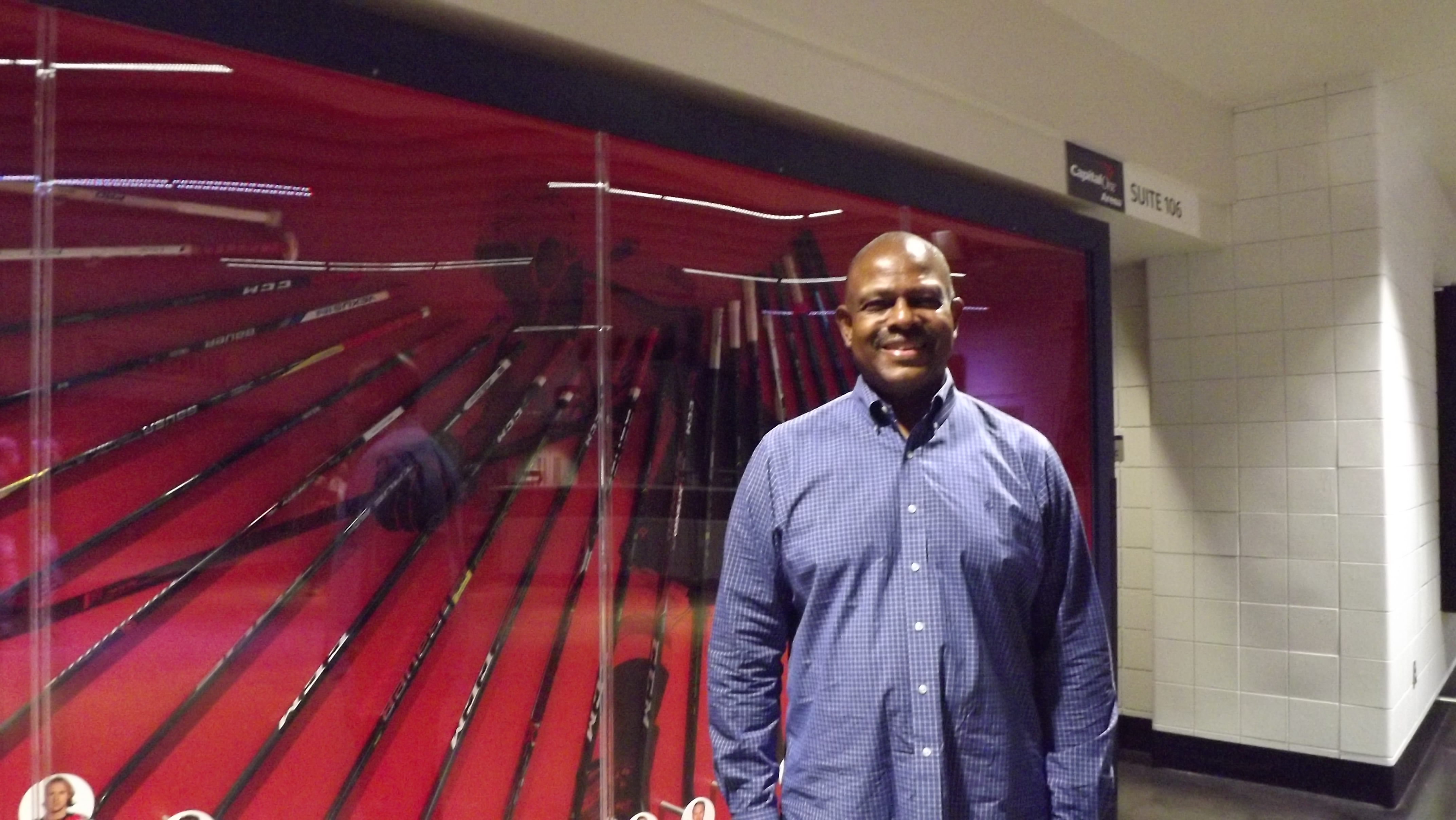 DC Board of Elections Chair Michael Bennett stands in front of a display of hockey sticks at Capital One Arena.