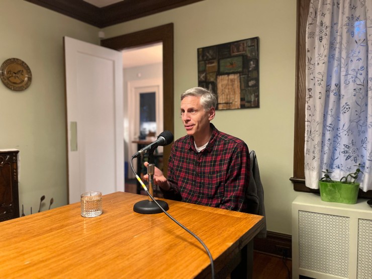 Jon Gertner, writer  of "The Idea Factory" sits astatine  a eating  country   array  and speaks into a microphone.