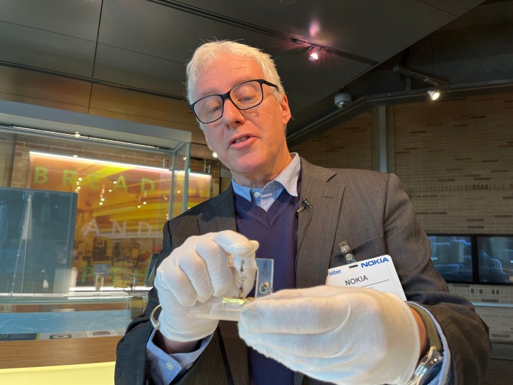 David Brancaccio holds the archetypal  transistor successful  his hands wearing gloves, astatine  Nokia Bell Labs successful  Murray Hill, New Jersey.