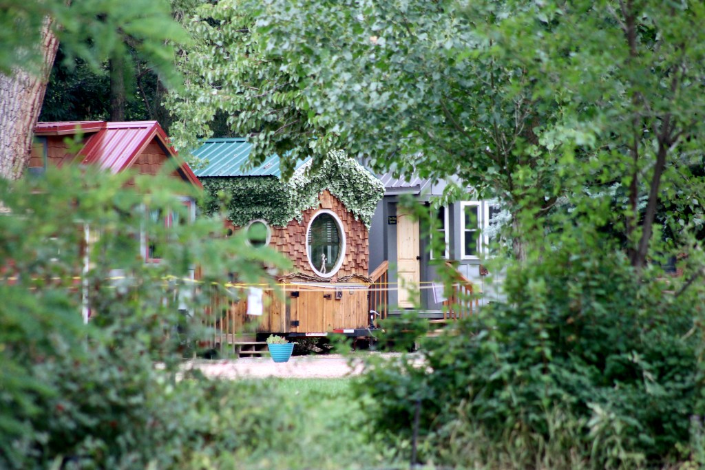 De minuscules maisons décorées de lierre et aux toits de couleurs vives se dressent au milieu d'une zone boisée.