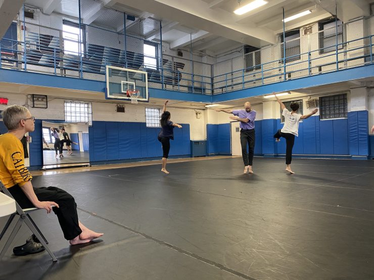 People dance and rehearse in an open, gymnasium space .