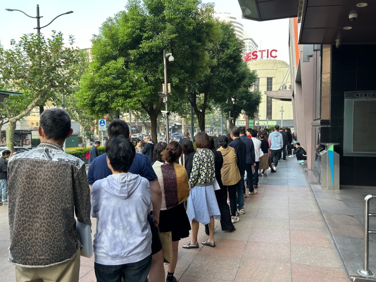 A line of people snakes along an office-like building.