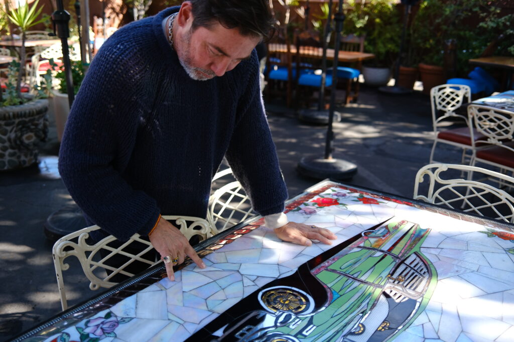 Casita del Campo owner Robert del Campo points out the stained glass details of tables in an outdoor dining area. 