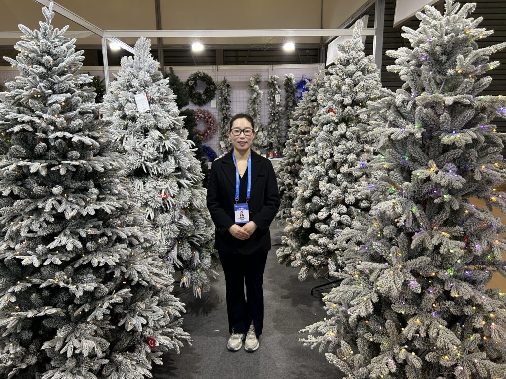 A woman stands in the middle of Christmas tree display.